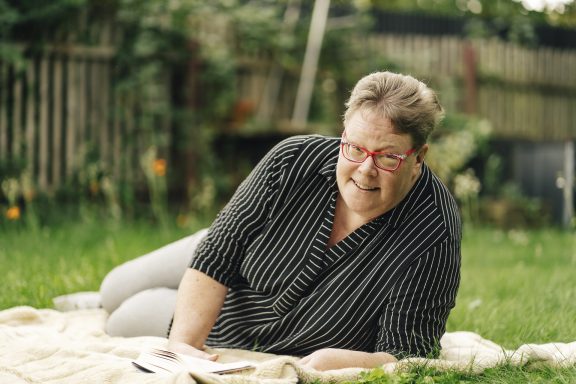 Wenn’s läuft Geli lacht, während sie auf einer Decke im Garten liegt.